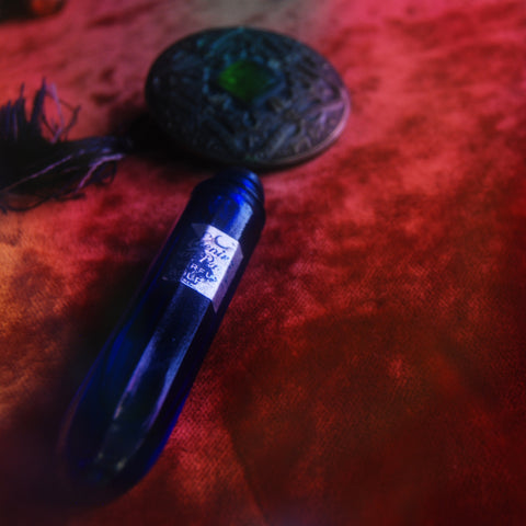 Vintage An Evening in Paris cobalt blue glass perfume bottle. Brass chain necklace with fringe tassel. Vintage ornate button.